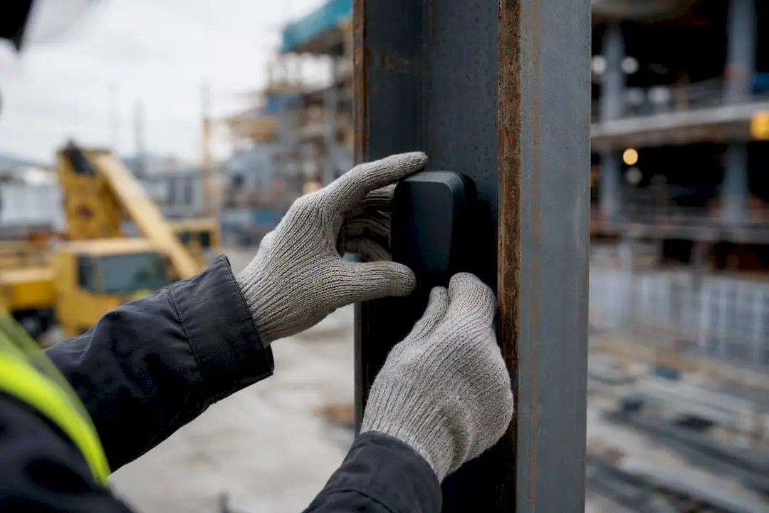 Hands installing safety sensor on steel beam