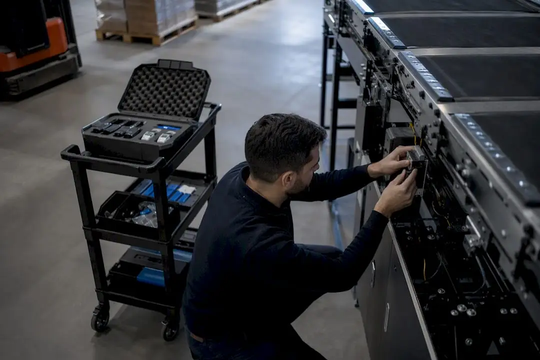 Technician installing sensor on conveyor in warehouse