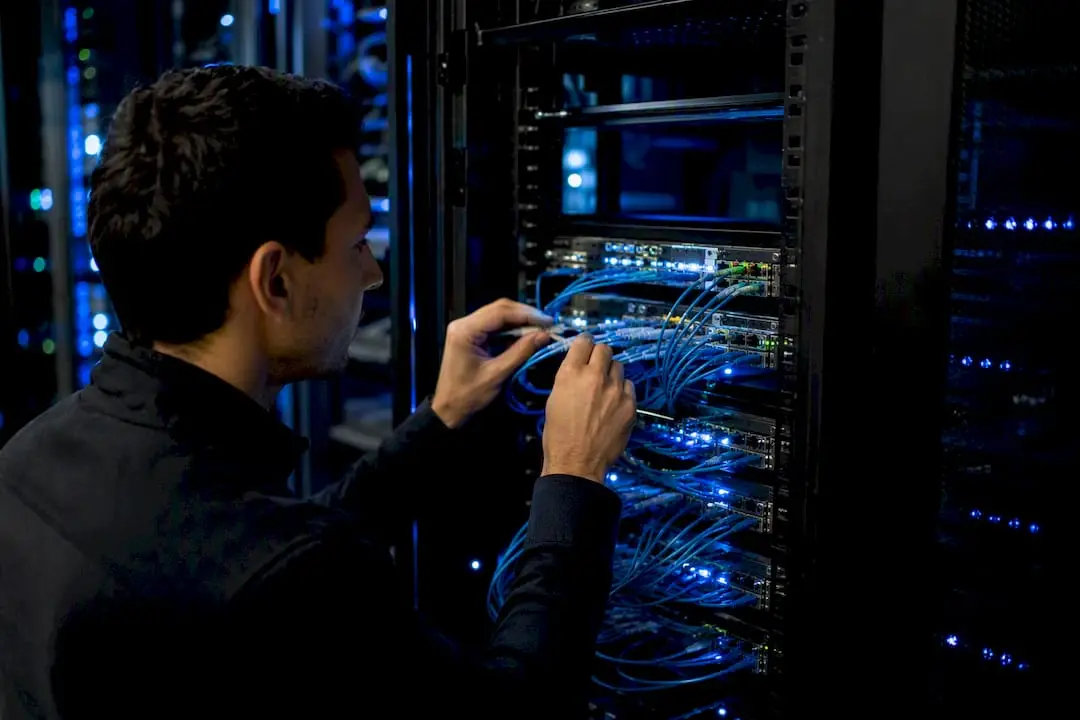 Hands adjusting fiber optic cables in server rack