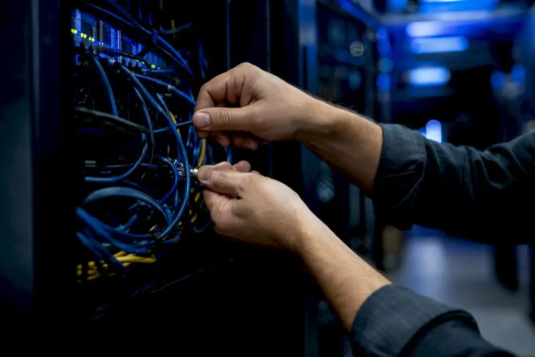 Hands adjusting network cables in server rack